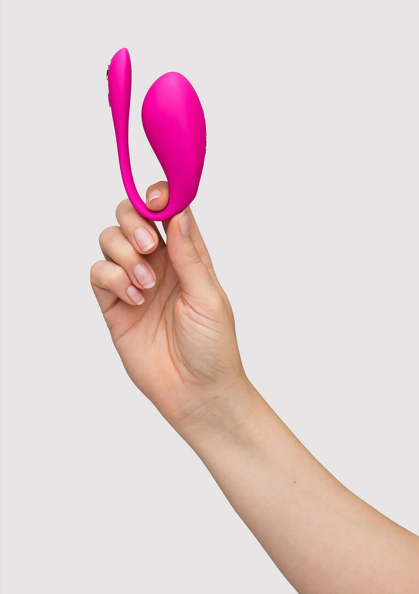 We-Vibe Jive 2 duo-vibrator in felroze in hand, staand op een vinger