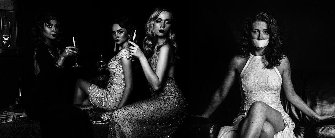 Black and white photo of four stylish women in elegant dresses, three holding glasses, one with tape over her mouth.