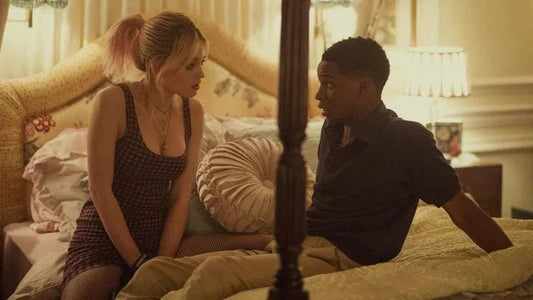 Young woman and man sitting on a bed in a softly lit bedroom, talking closely