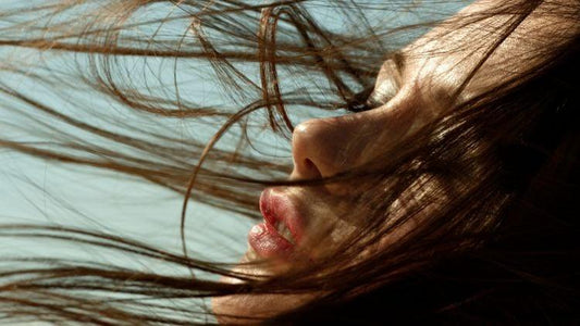 Close-up of woman's face with long hair blowing in wind, lips slightly parted
