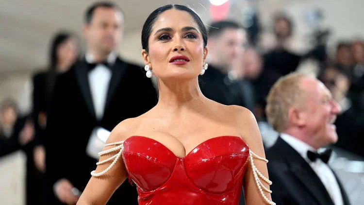 Woman in a glossy red strapless gown with pearl chain shoulder details at a formal black-tie event