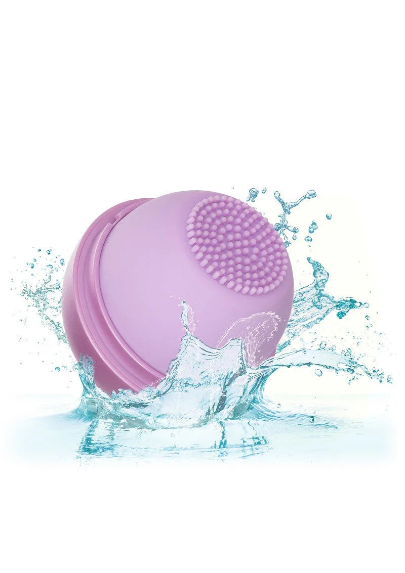 Purple silicone facial cleansing brush splashing in water, waterproof skincare tool