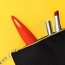 Black textured makeup pouch with red vibrator and red lipstick on yellow background