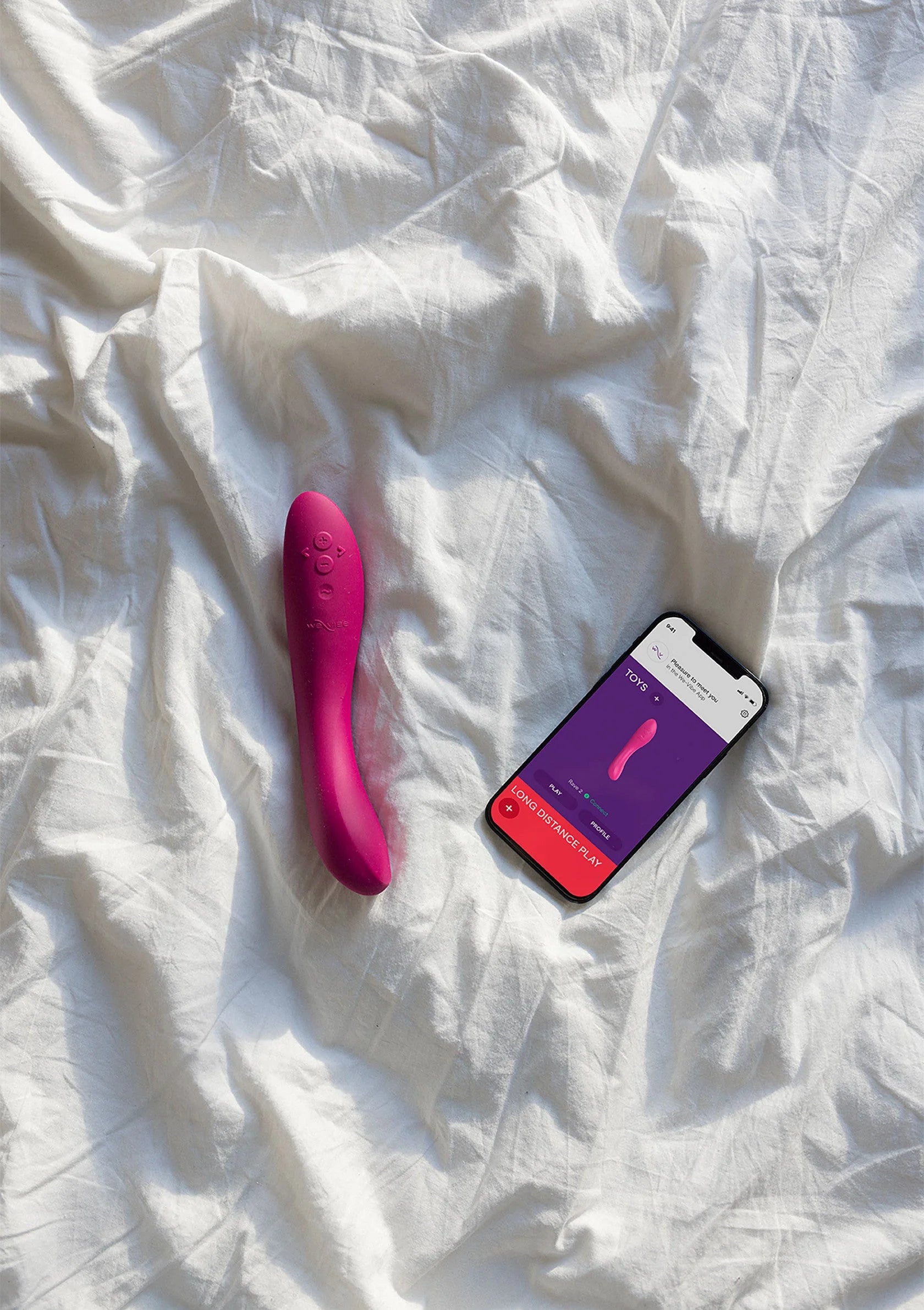 Roze vibrerende stimulator op bed met smartphone en productkaart