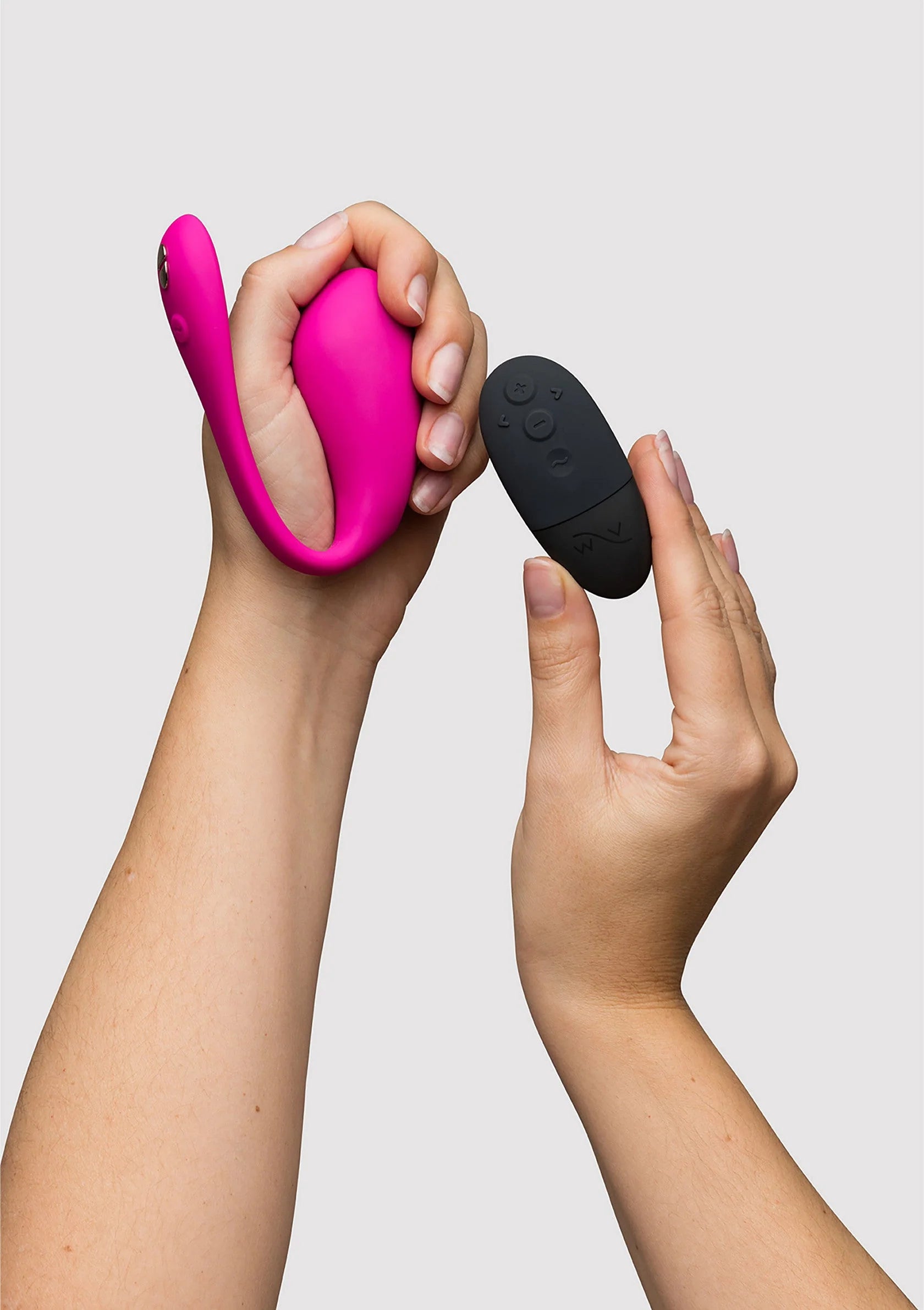 Fuchsia vibrator in hand met zwarte afstandsbediening in andere hand