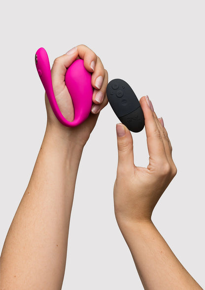 Fuchsia vibrator in hand met zwarte afstandsbediening in andere hand
