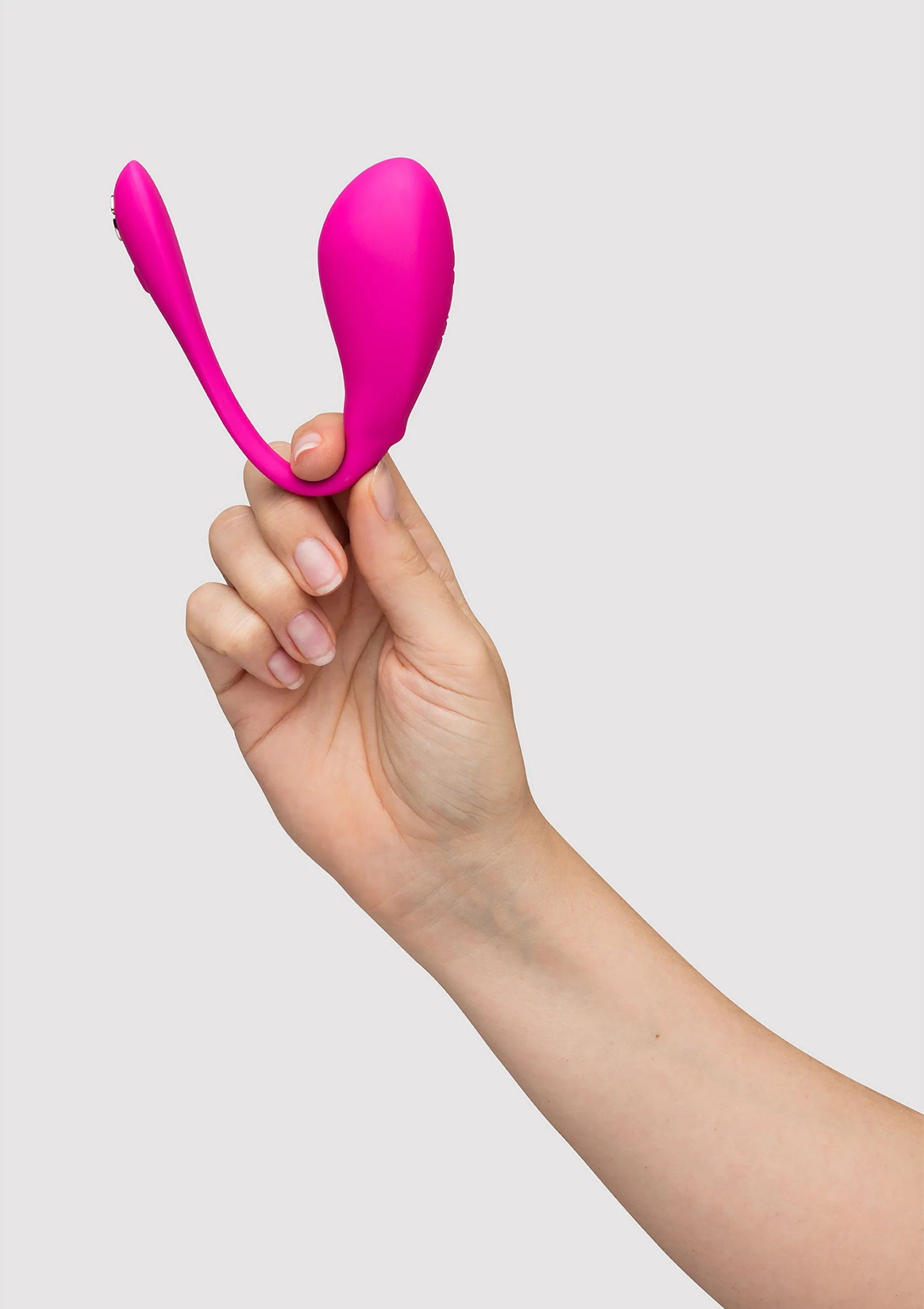 Fuchsia vibrator in de hand, met gebogen vorm en knopuiteinde