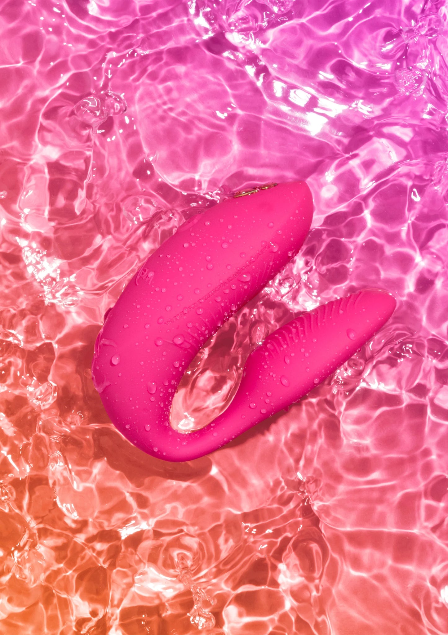 Chorus Pro van We-Vibe, roze koppelvibrator met waterdruppels op het oppervlak
