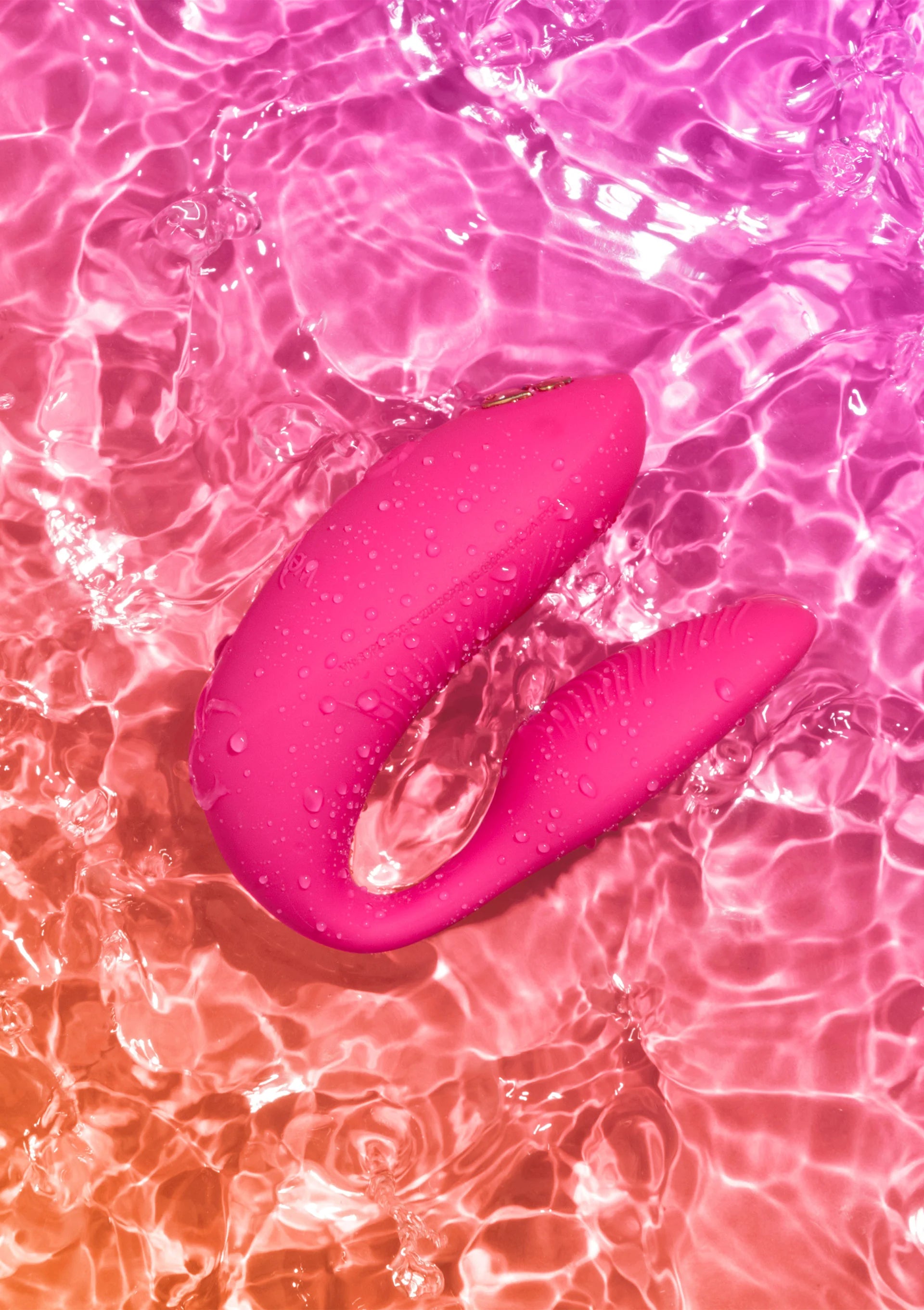 Chorus Pro van We-Vibe, roze koppelvibrator met waterdruppels op het oppervlak