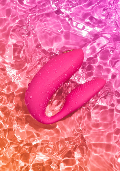 Chorus Pro van We-Vibe, roze koppelvibrator met waterdruppels op het oppervlak