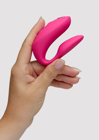 Chorus Pro van We-Vibe, roze koppelvibrator in hand, gebogen ontwerp