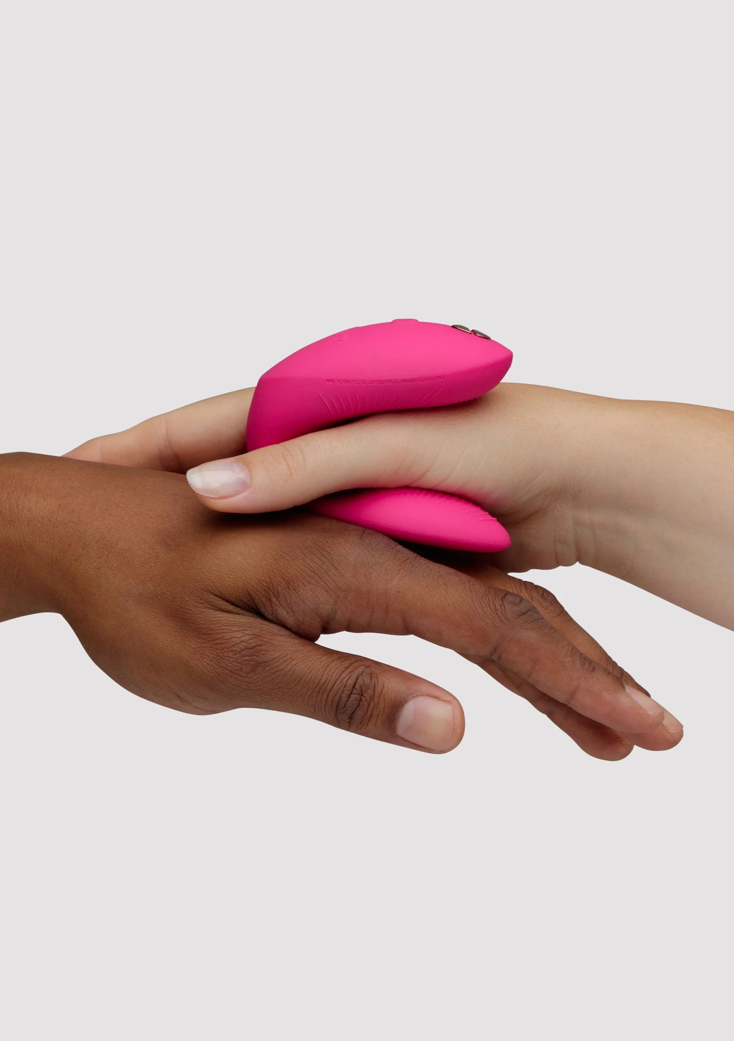 Chorus Pro van We-Vibe, roze koppelvibrator tussen handen, afgeronde uiteinden