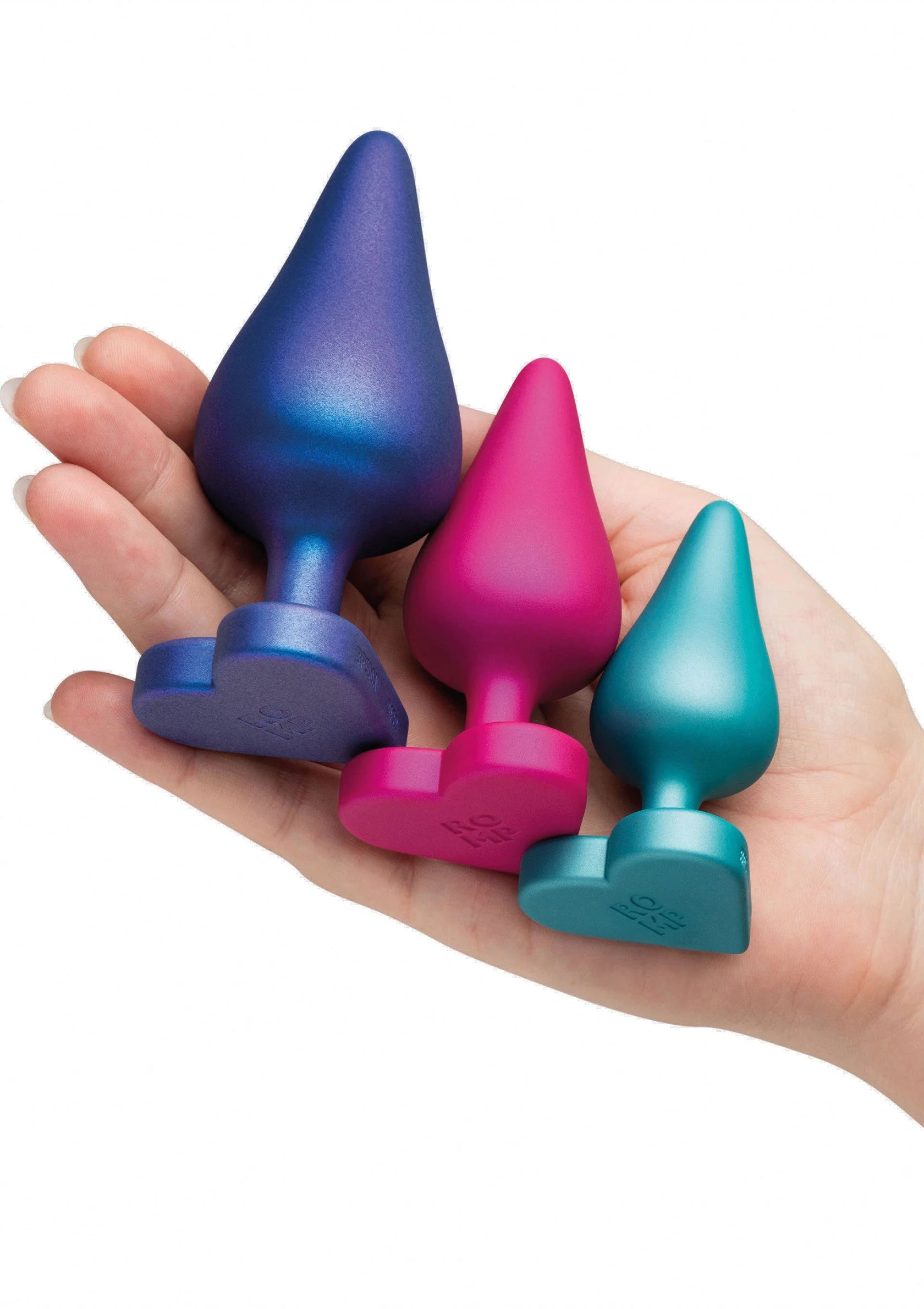 Anale trainingsset vastgehouden in hand: vier conische plugs in blauw, roze en teal.