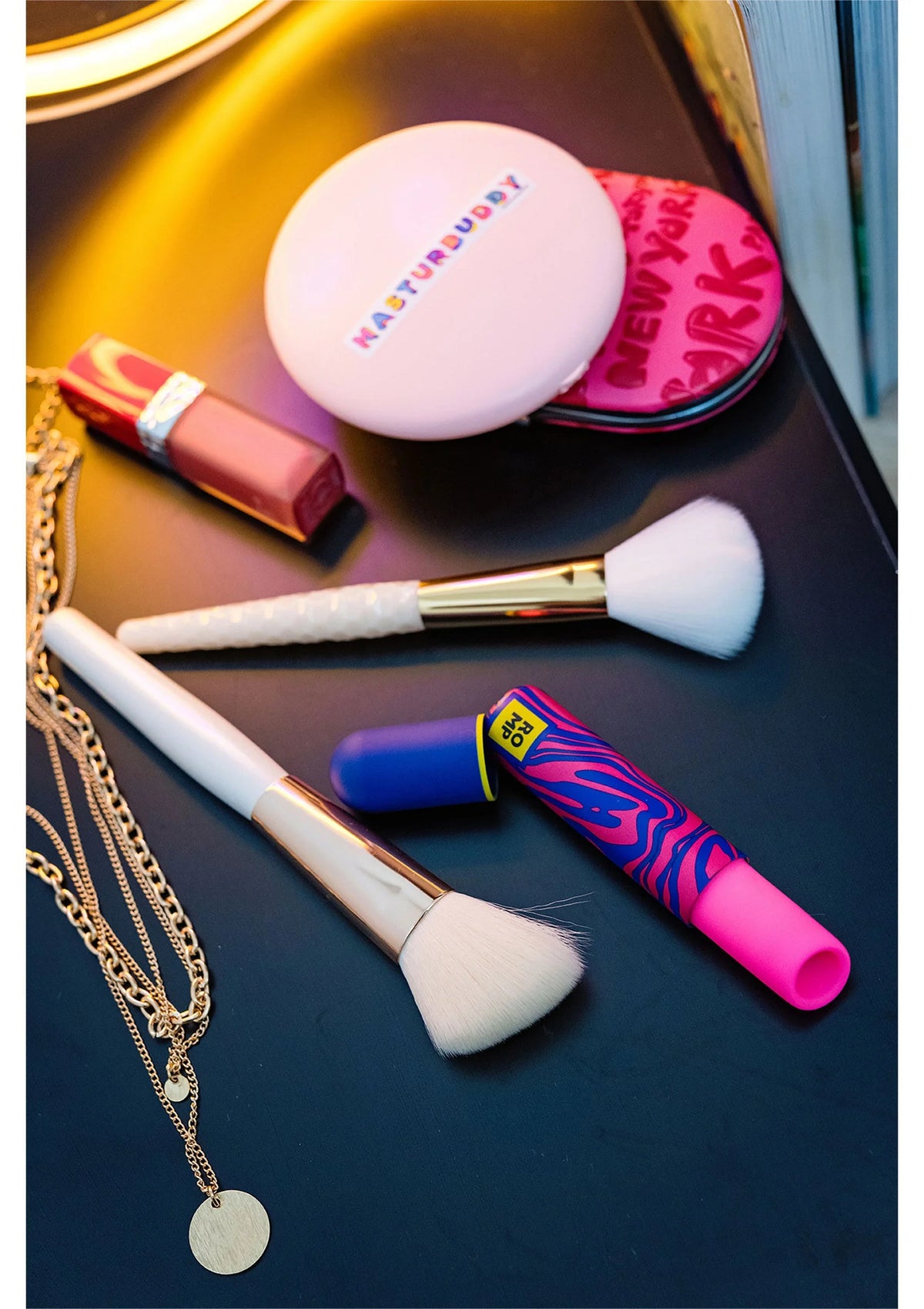 Airpressure-lipstick van Romp met blauwe en roze details, tussen make-up items op tafel