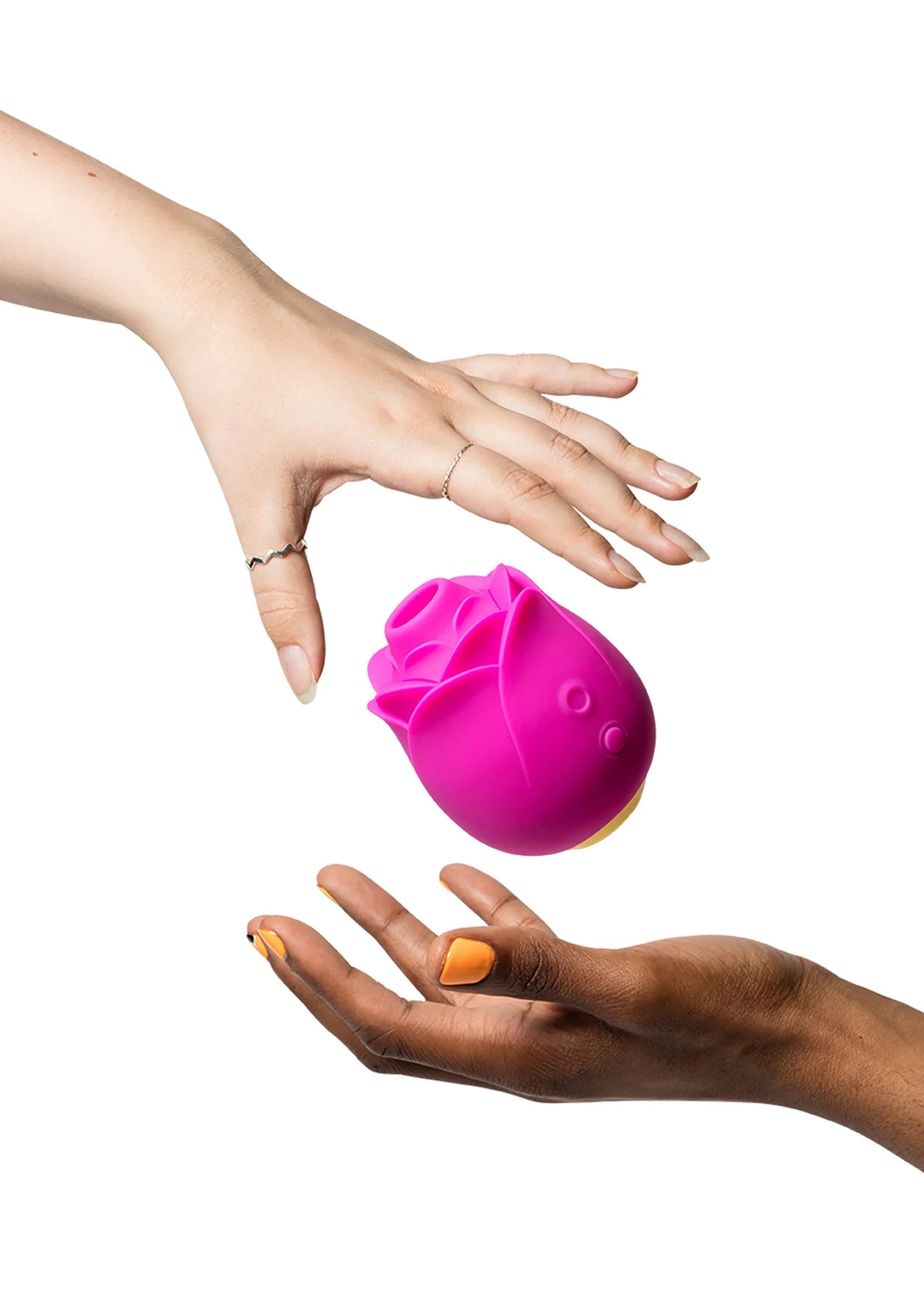 Roze lucht-druk massager tussen twee handen, siliconen knop en greep zichtbaar