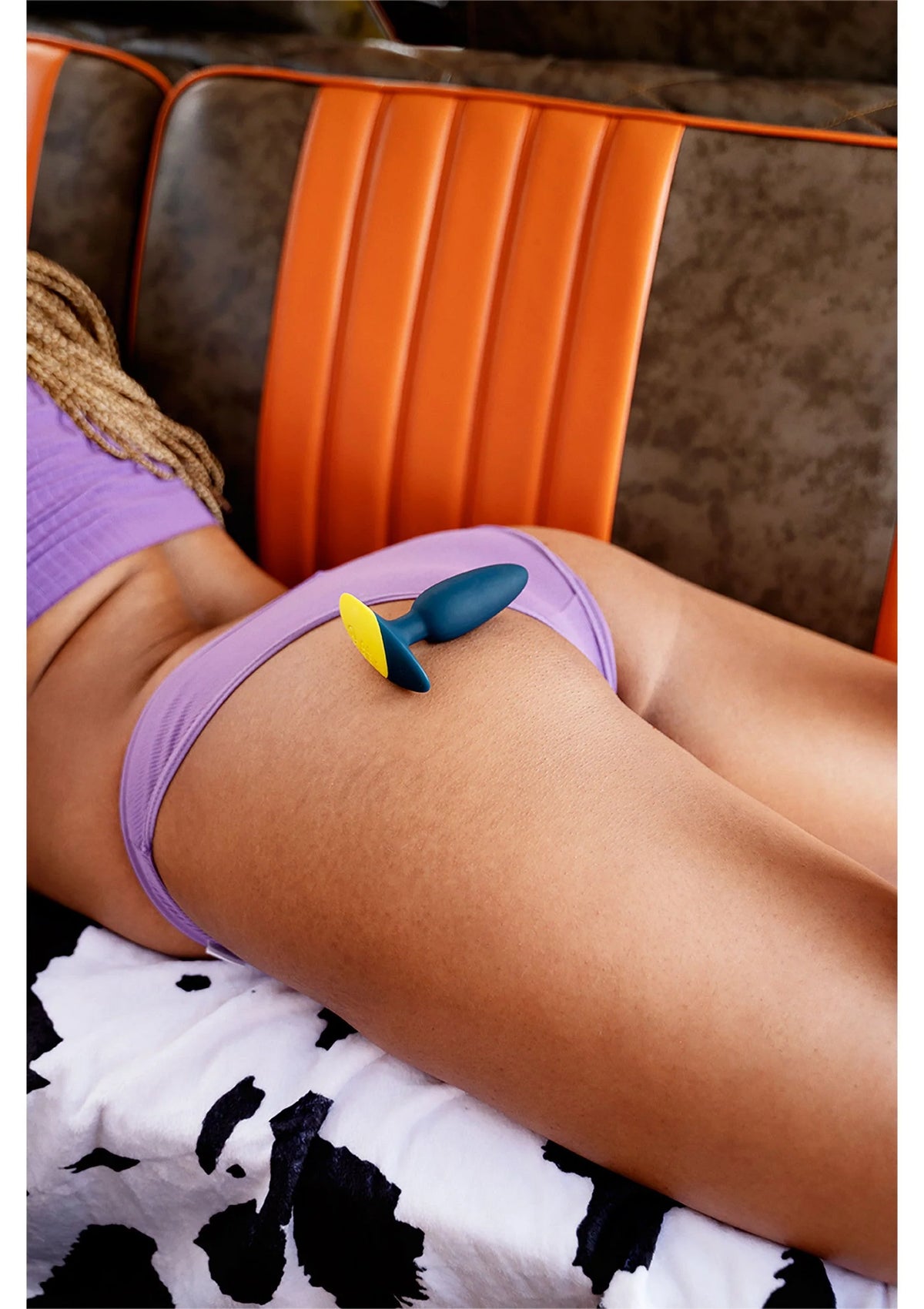 Vibrerende anaalplug in blauw met gele punt, zichtbaar op onderlichaam in paarse lingerie.