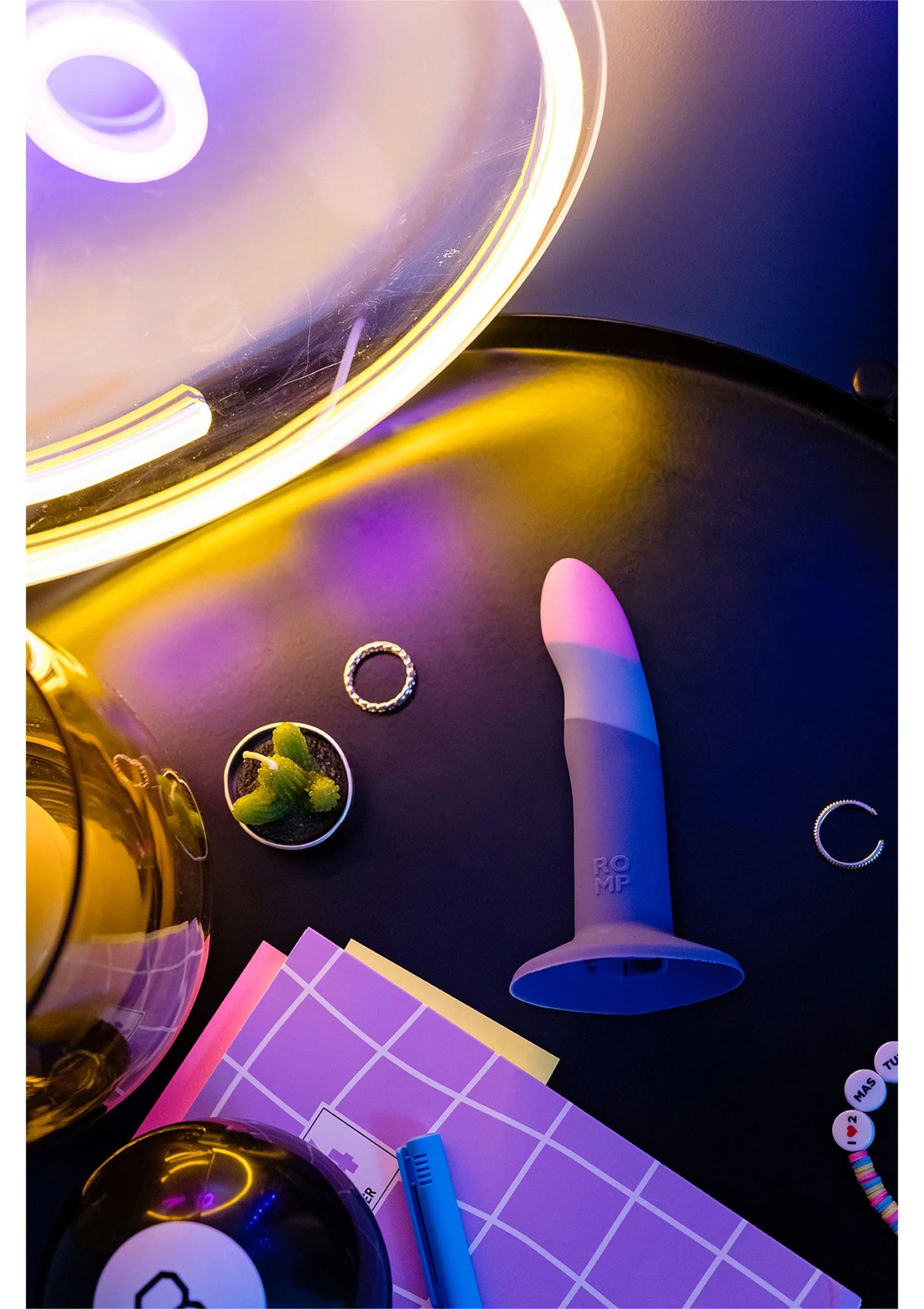 Blauwe dildo met paarse top in scène met spiegels en fel licht