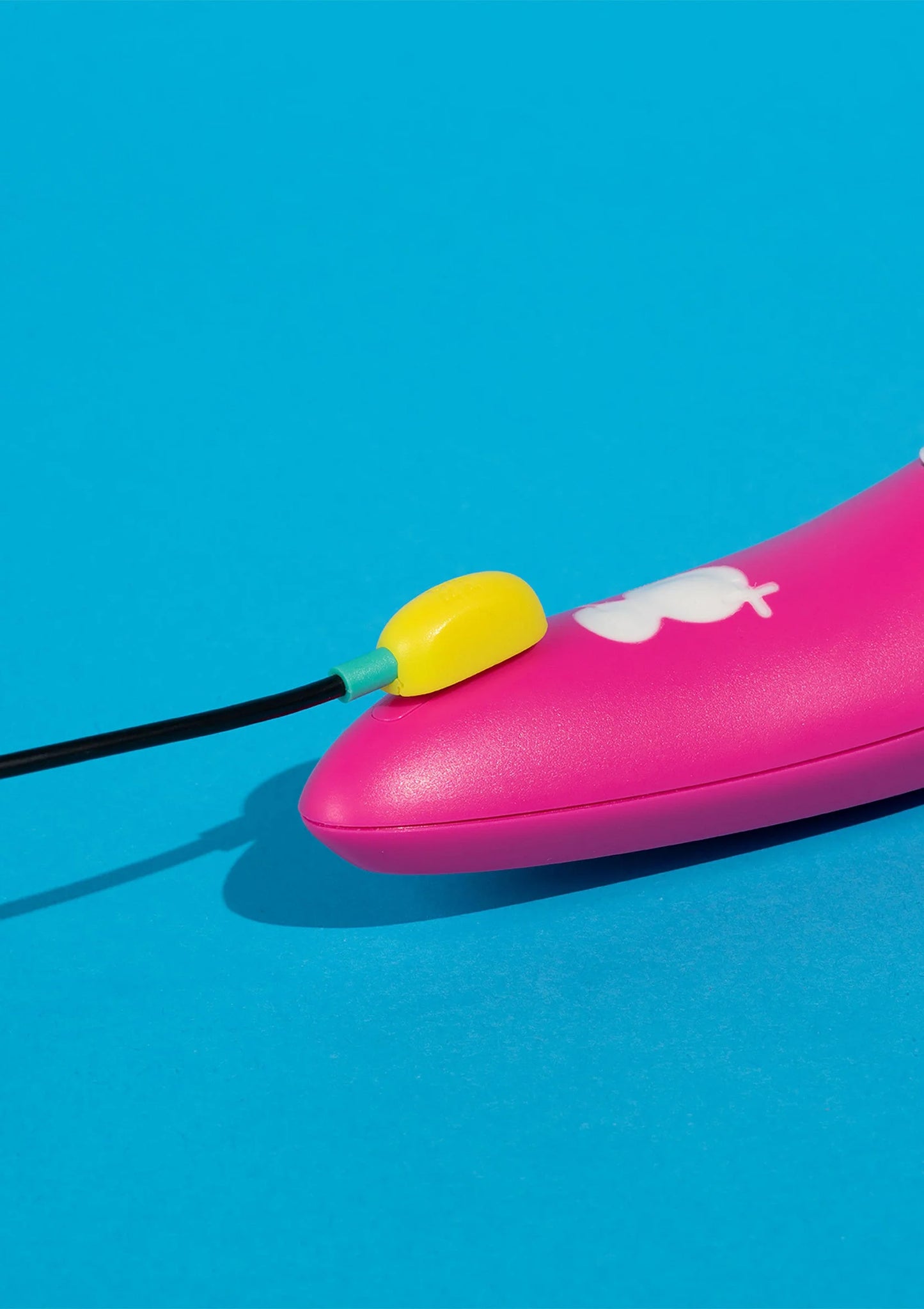 Roze vibrator met zwarte kabel en gele knop, wit opzetstuk