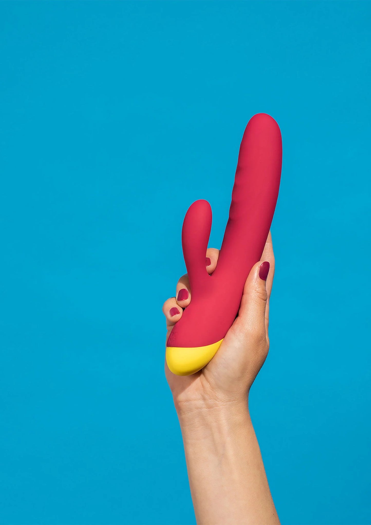 Rode seksvibrator met gele basis, vastgehouden door een hand