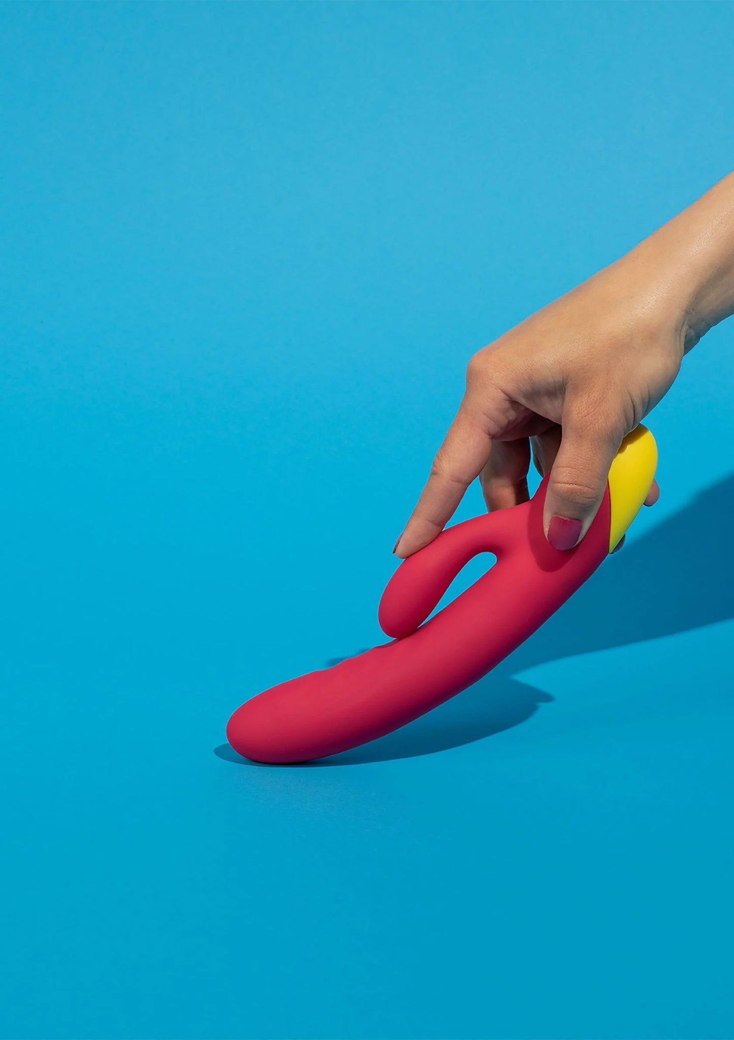 Rode seksvibrator met gele basis, met hand op het apparaat