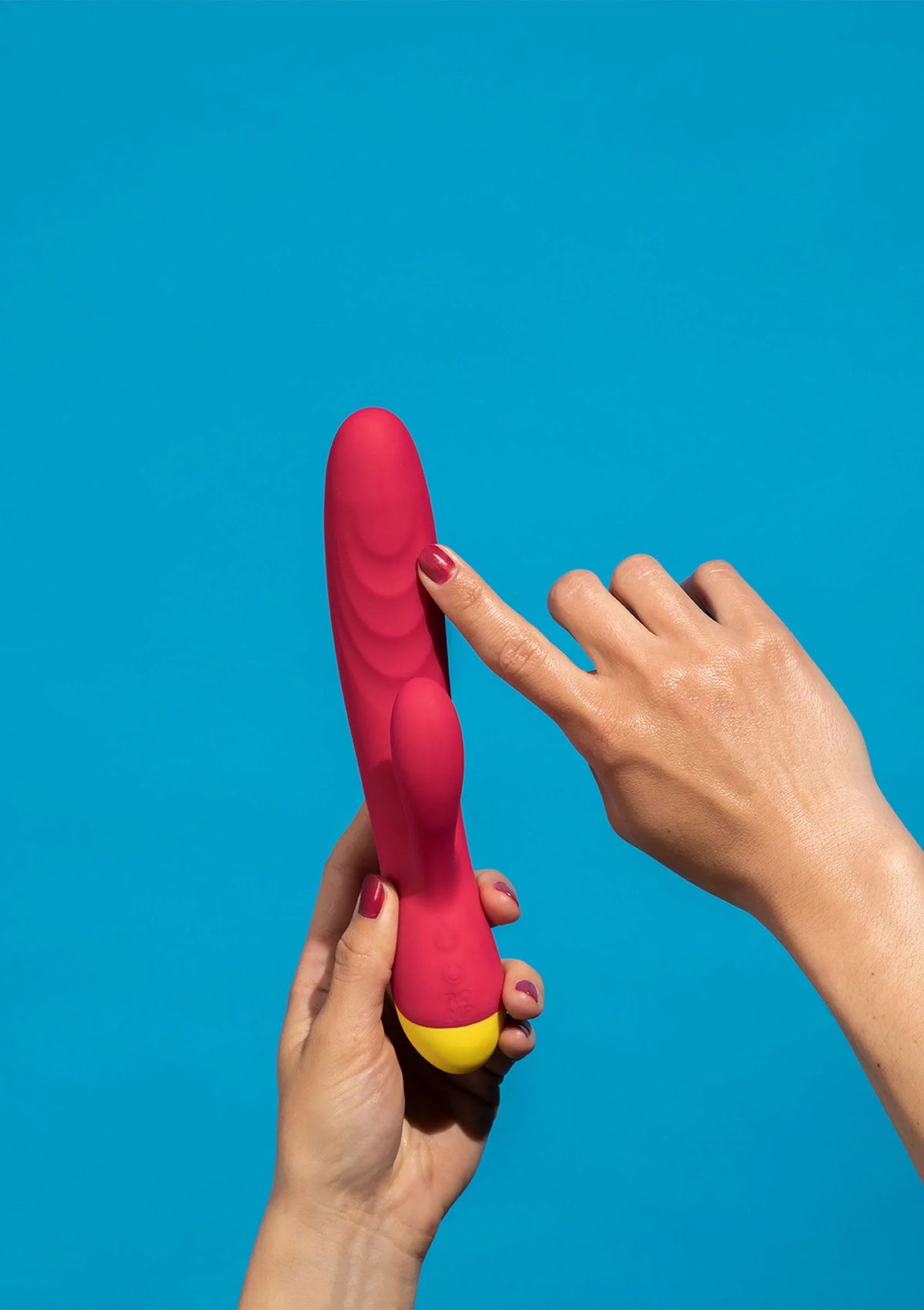 Rode seksvibrator met gele basis, rechtop gehouden door een hand