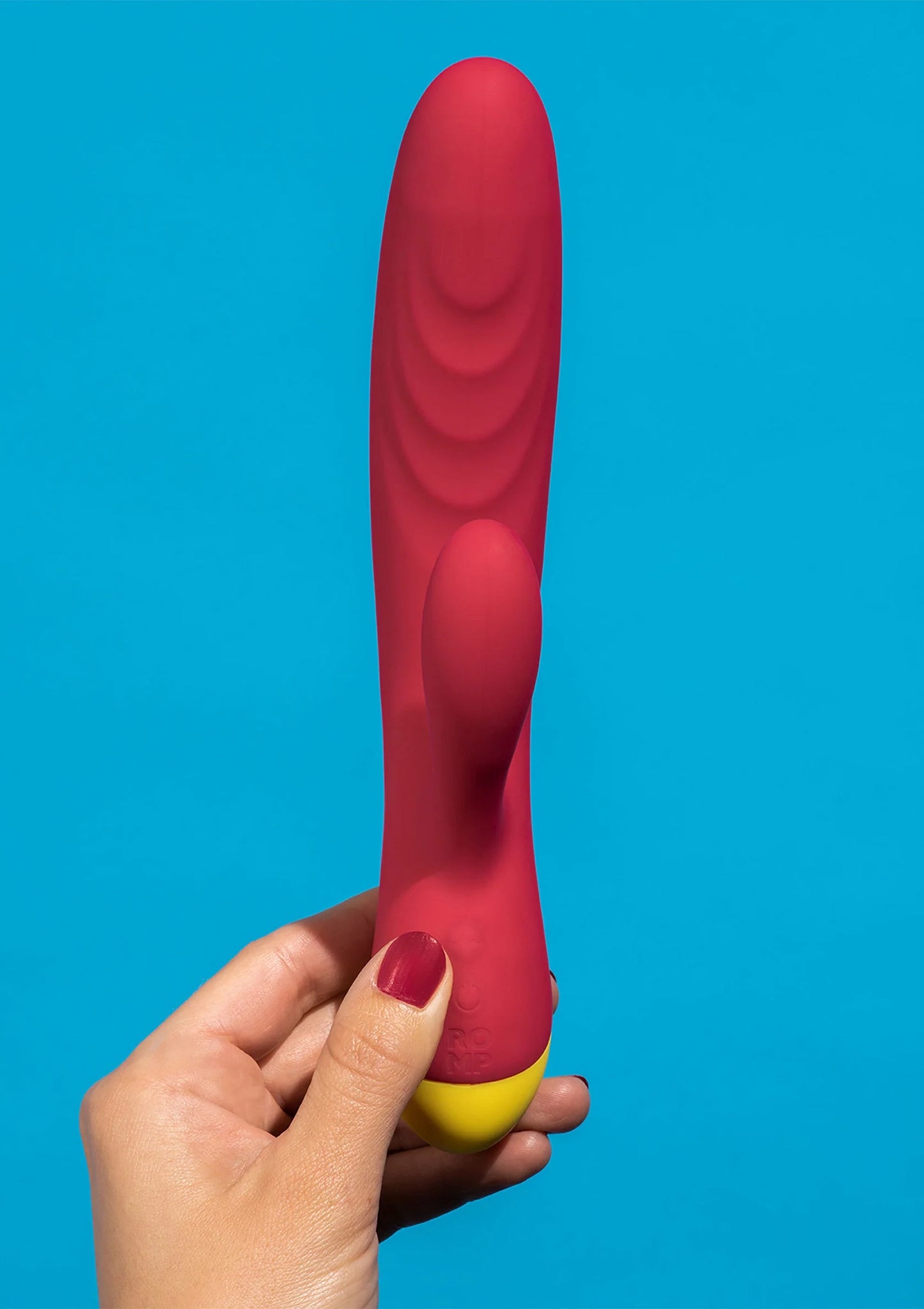 Rode seksvibrator met gele basis, omhoog gehouden in een hand