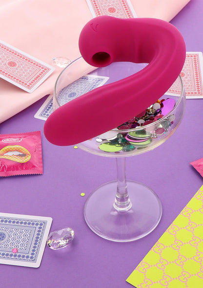 Roze clitorisvibrator op tafel, gebogen vorm met ronde kop en zichtbare opening