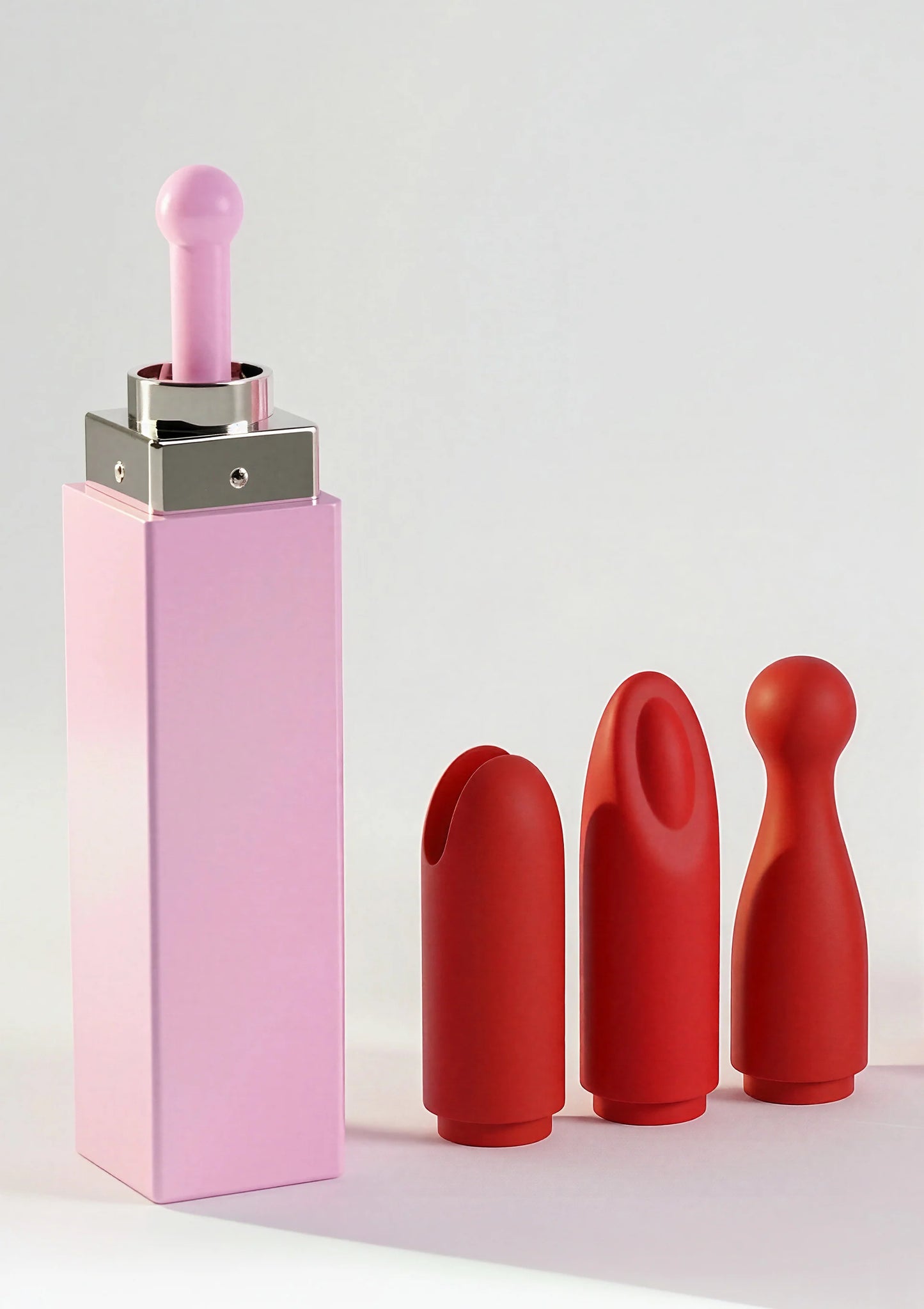 Roze lipstick-vibrator van Xocoon met rood opzetstuk en twee rode kappen en losse paars