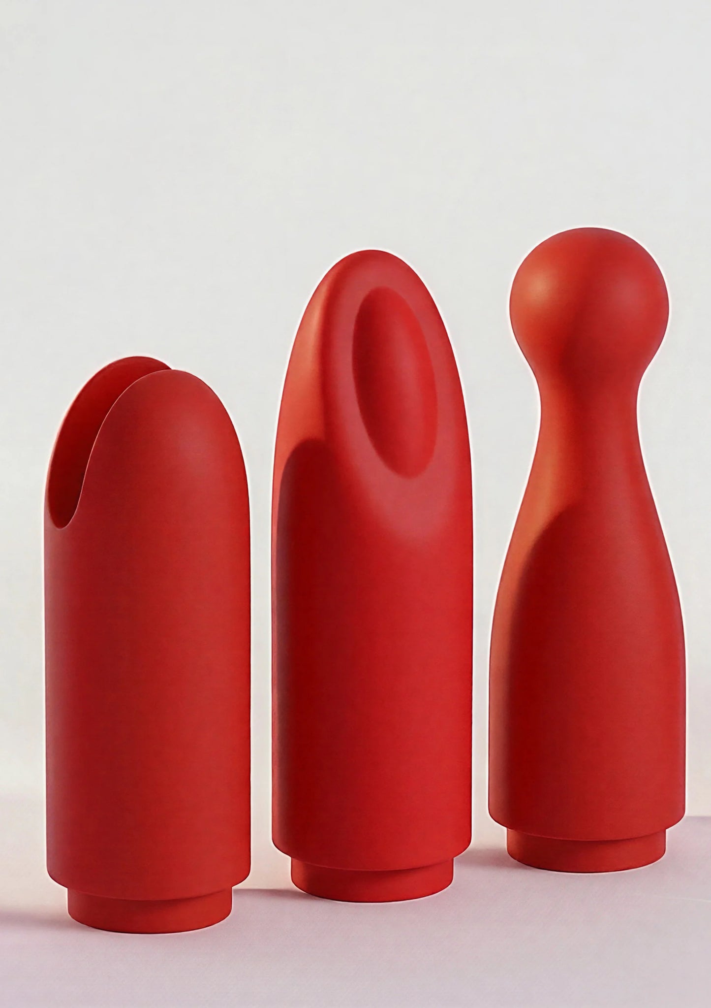 Drie rode lipstick-vibrator kappen/opzetstukken in verschillende vormen op een rij