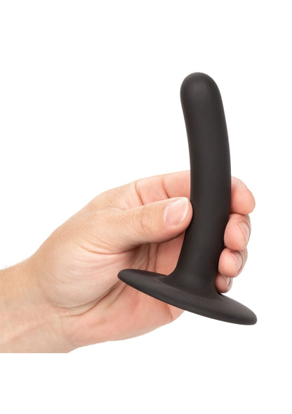 Zwarte slanke dildo met platte zuignapvoet, vastgehouden door hand