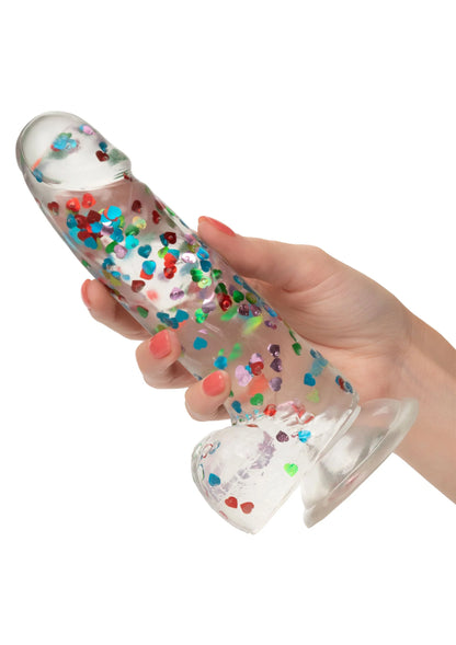 Hand die transparante dildo vasthoudt met gekleurde hartjesprint en ronde voet