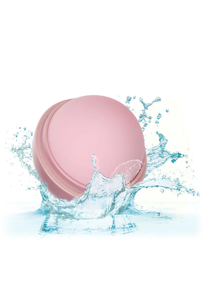 Roze massagebol onder water met spetters rond de bol