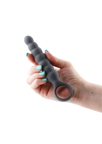 Donkere anale plug in de hand, met geribbelde schacht en ronde ring