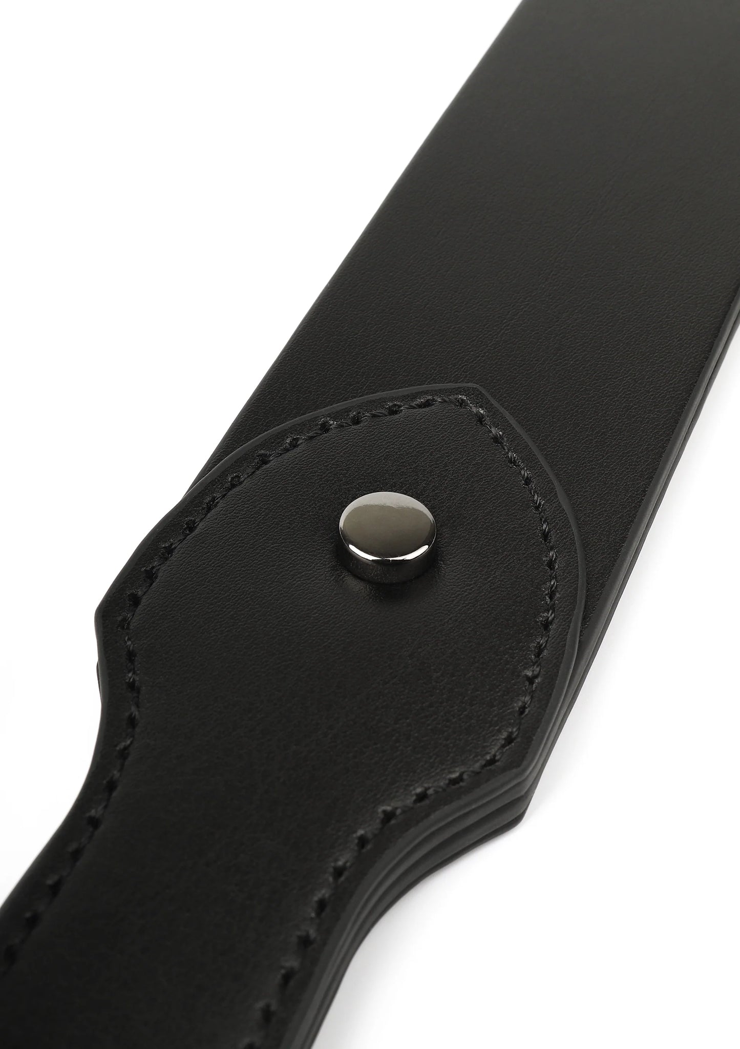 Detail van zwarte leren slapper: ronde metalen drukknop op afgeronde flap