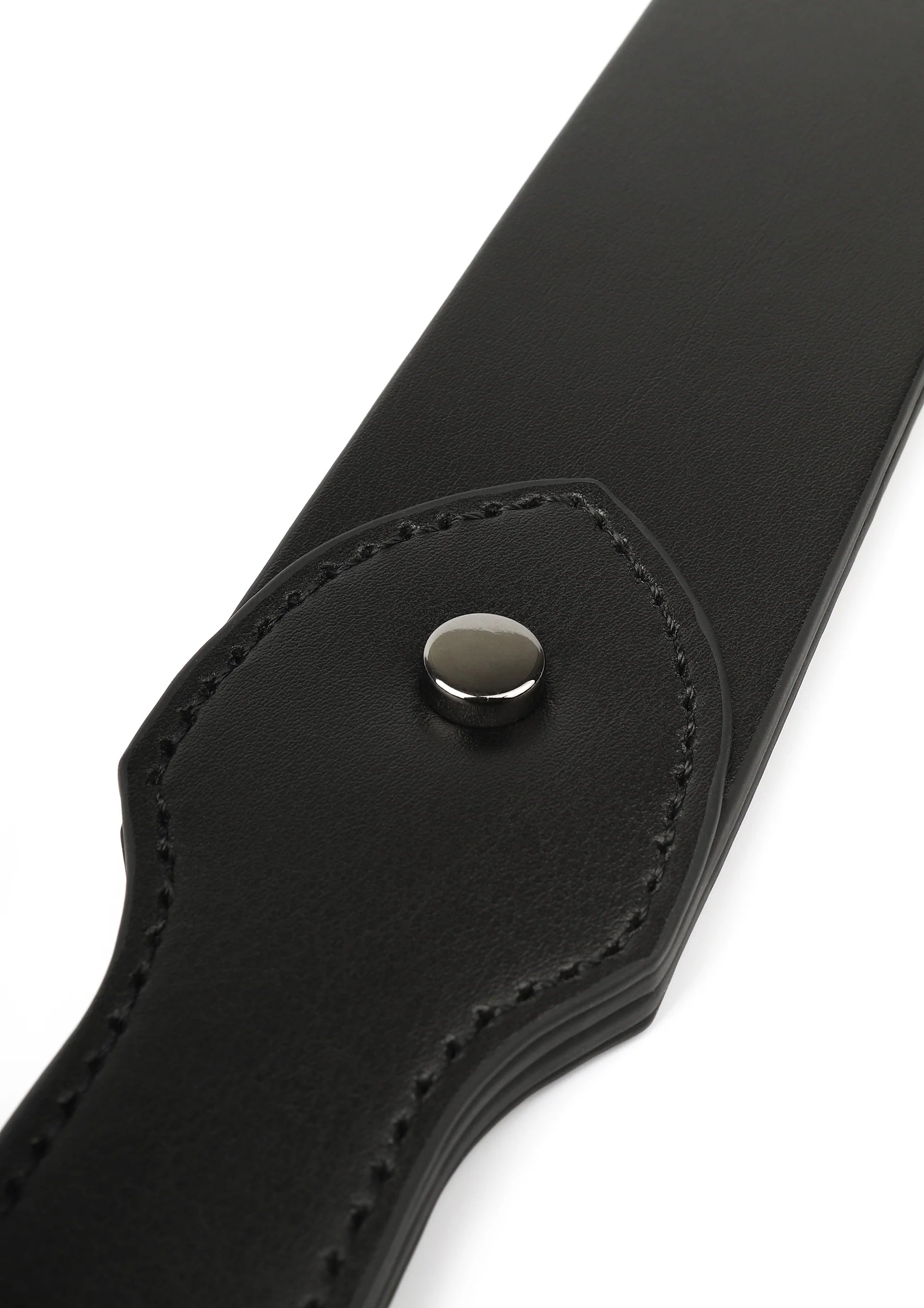 Detail van zwarte leren slapper: ronde metalen drukknop op afgeronde flap