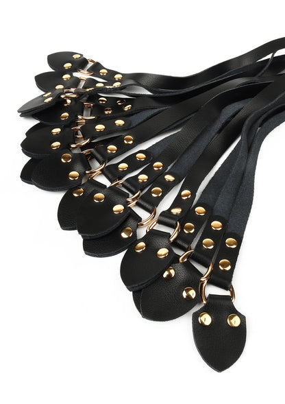 Close-up van zwarte leren zweeptongen met gouden metalen studs en zwarte riemen