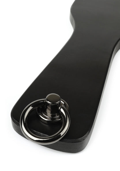 Spankpeddel van echt leer, zwart met ronde metalen ring en knoop, close-up