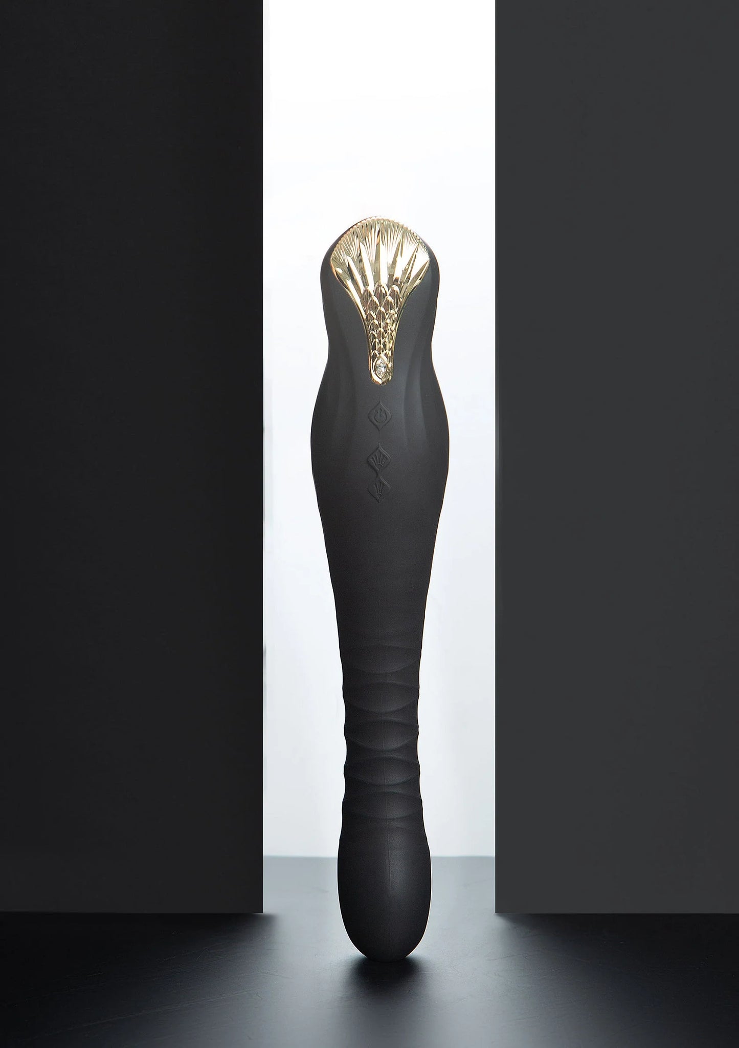 Zwarte dildo met goudkleurige kop en glanzende ribbels aan de bovenkant.