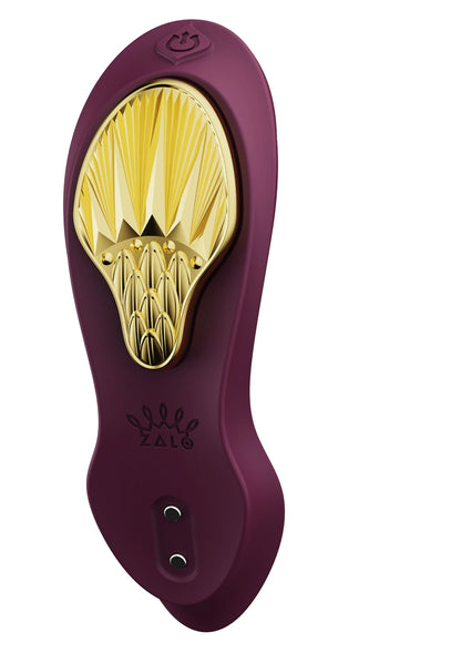 Draagbare vibrator in paars met gouden ovale kop, power-icoon boven en twee openingen onder.