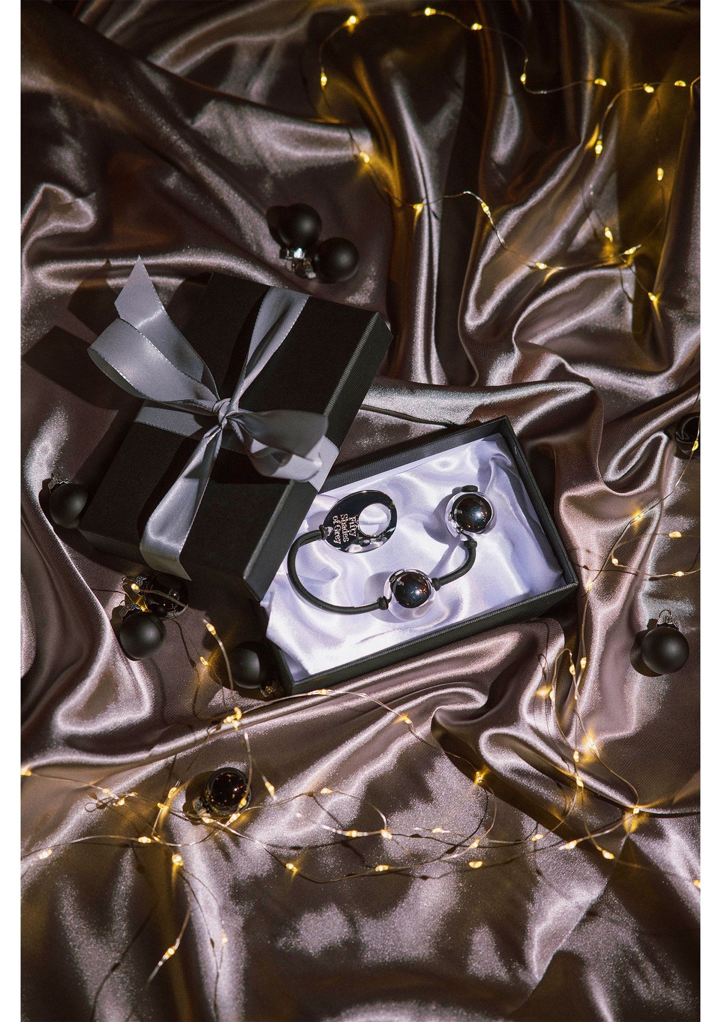 Zilveren pleasure balls met zwart koord op zilvergrijze satin