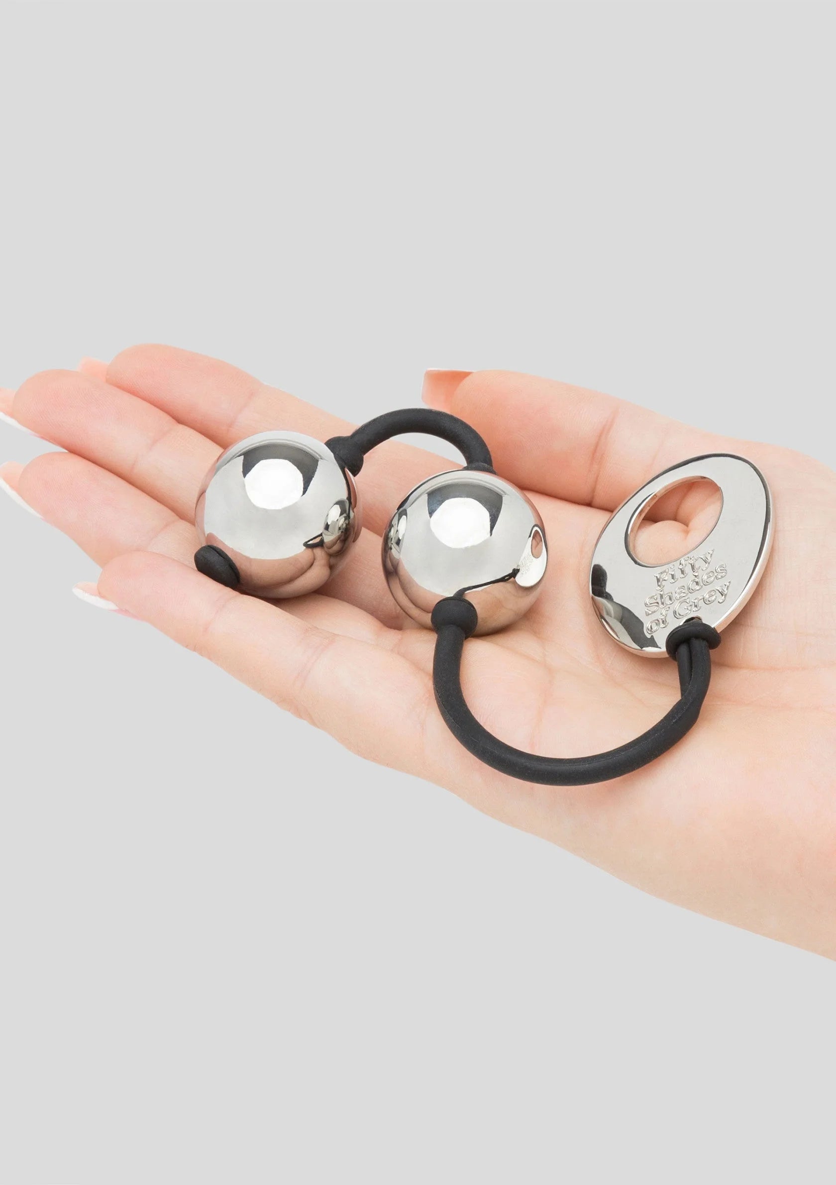 Zilverkleurige metalen pleasure balls in hand met zwart koord