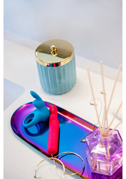 Blauwe cockring met roze inzet, op tafel naast sieraccessoires