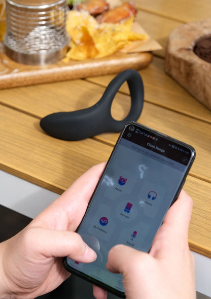 Zwarte vibrerende cockring terwijl smartphone de app met bediening toont