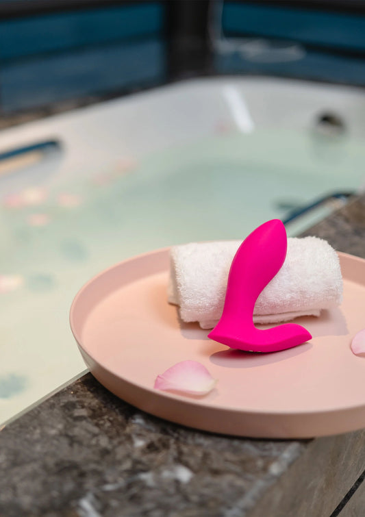 Roze koppelvibrator met twee uiteinden op een opgerolde badhanddoek