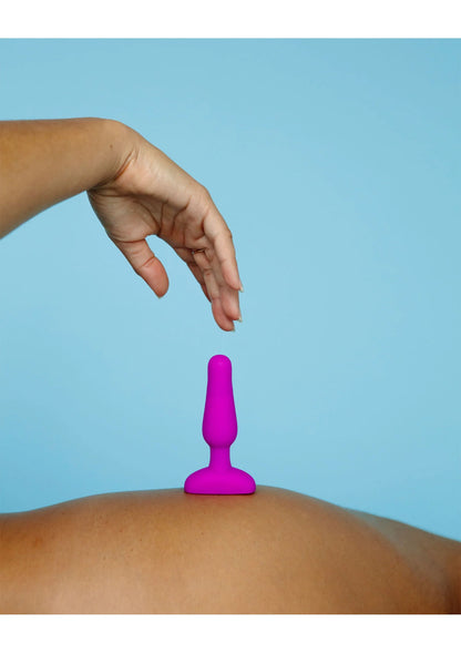 B-Vibe novice plug in fuchsia op de huid, met hand die aanreikt