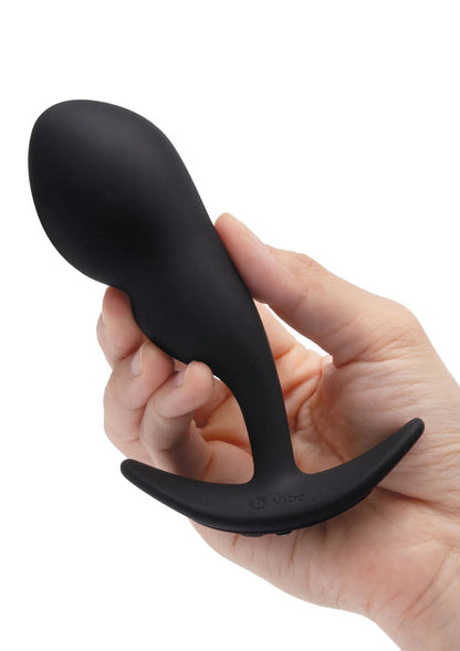 Zwarte P-spot snug plug met afgeronde punt en brede flens, vastgehouden in hand