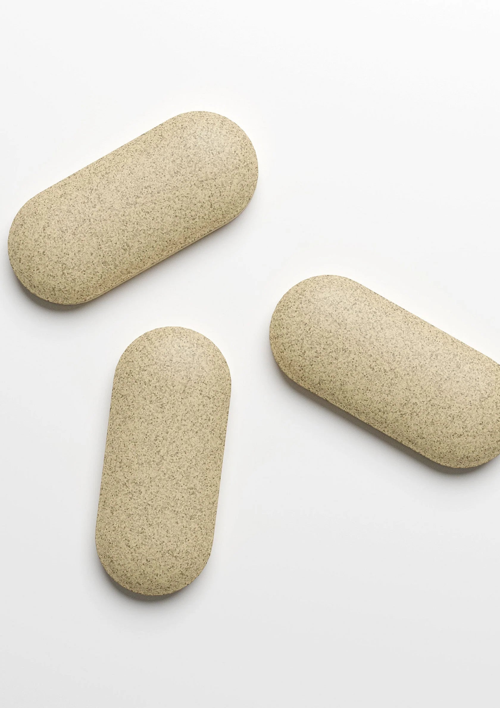 Beige supplementtabletten, drie stuks op een witte ondergrond