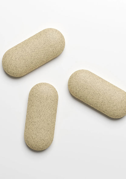 Beige supplementtabletten, drie stuks op een witte ondergrond