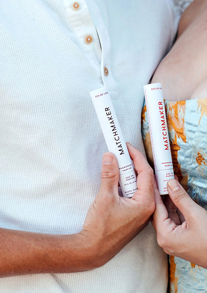 Rode parfumsprayfles in hand, naast doos vooraan zichtbaar
