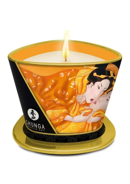 Massagekaars Shunga met kaarsvlam, oranje decoratieve illustratie, zwarte houder en goudkleurige voet.